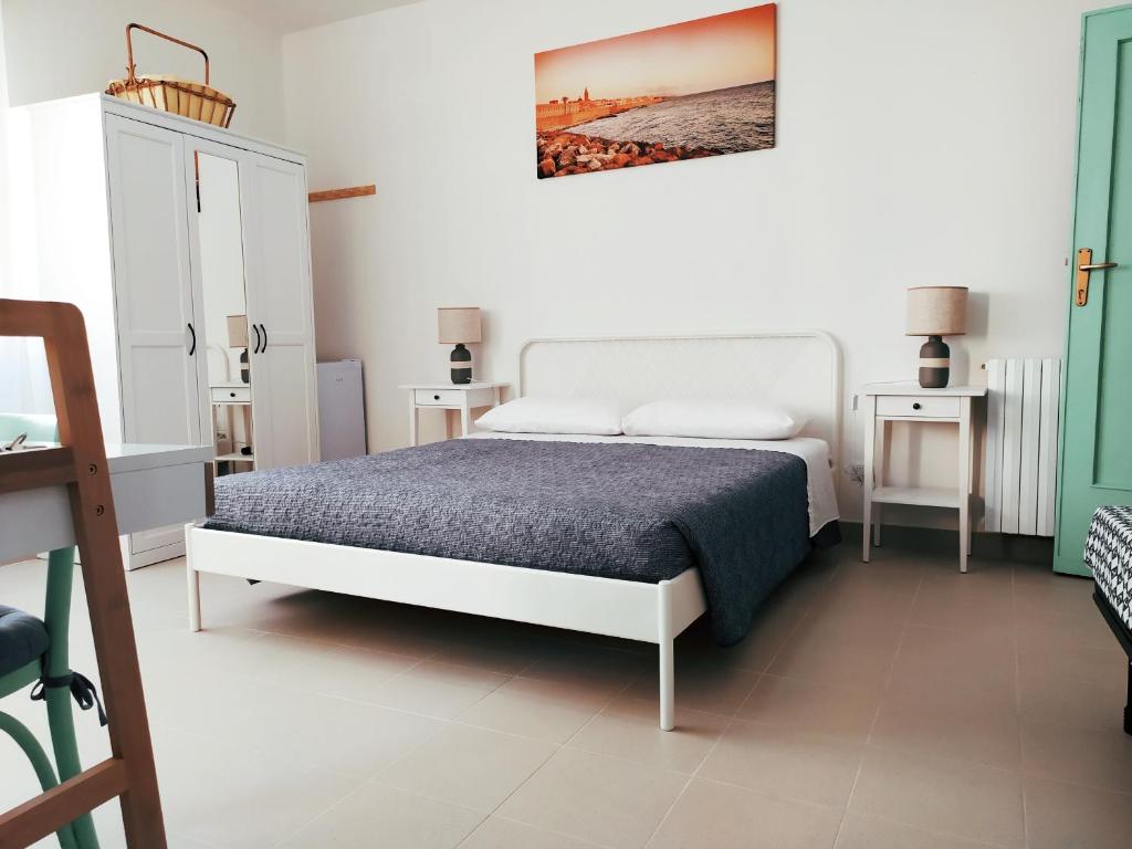 Lo Spicchio b&b في ألغيرو: غرفة نوم بيضاء مع سرير وطاولتين