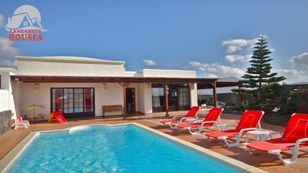 a villa with a swimming pool and red chairs at Villa Celeste in Playa Blanca