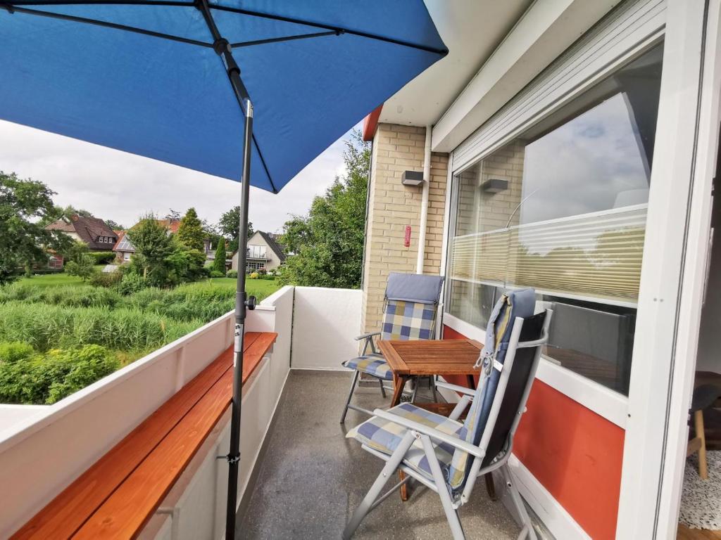 a patio with a table and chairs and an umbrella at Ferienwohnung Ebbe & Flut in Horumersiel