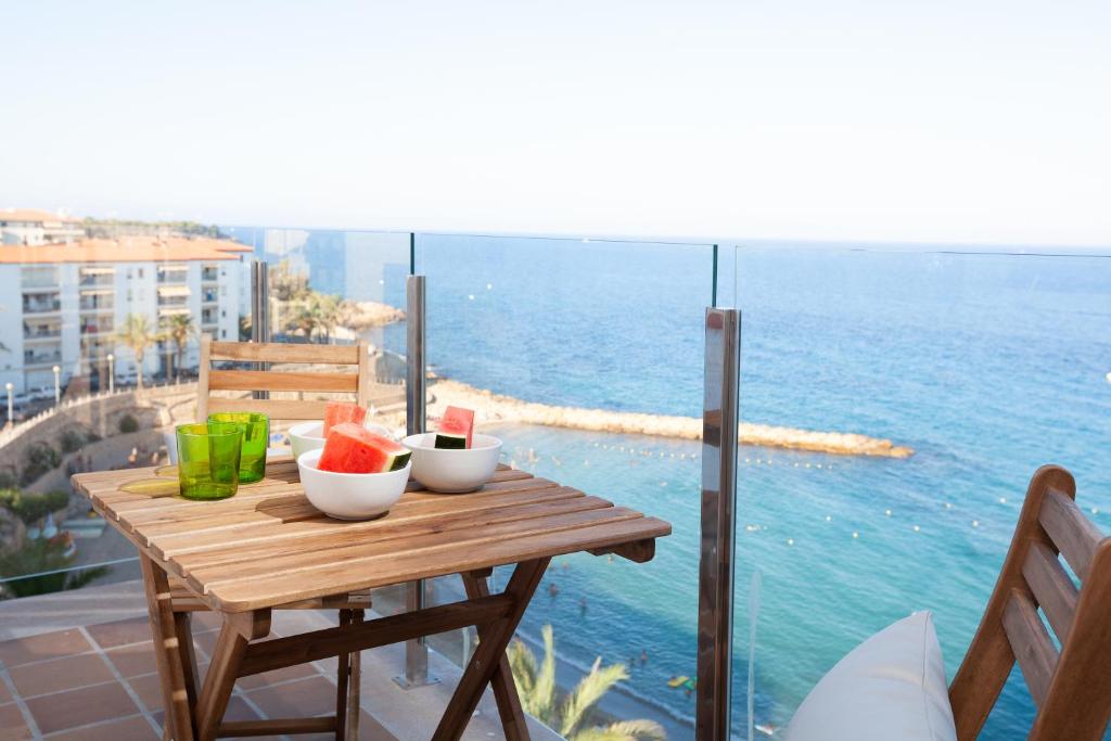 a table with fruit on a balcony with the ocean at LA CALA BEACH DELUXE Apartments in L'Ametlla de Mar