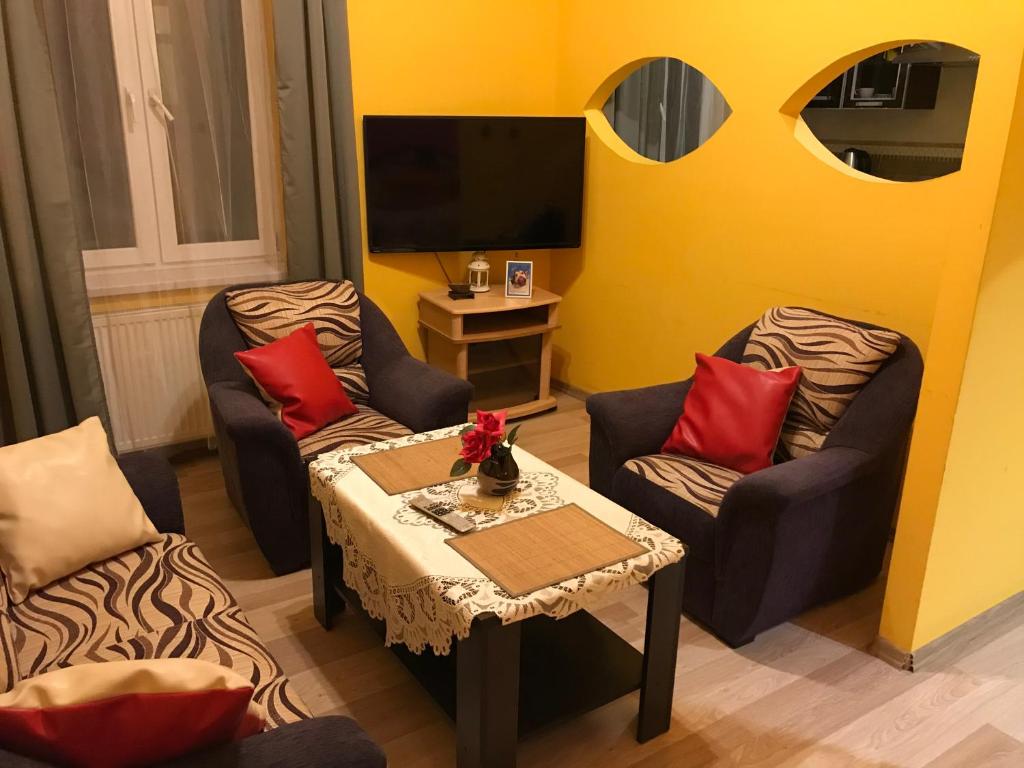 sala de estar con 2 sillas, mesa y TV en Apartamenty AS Topolowa, en Cracovia