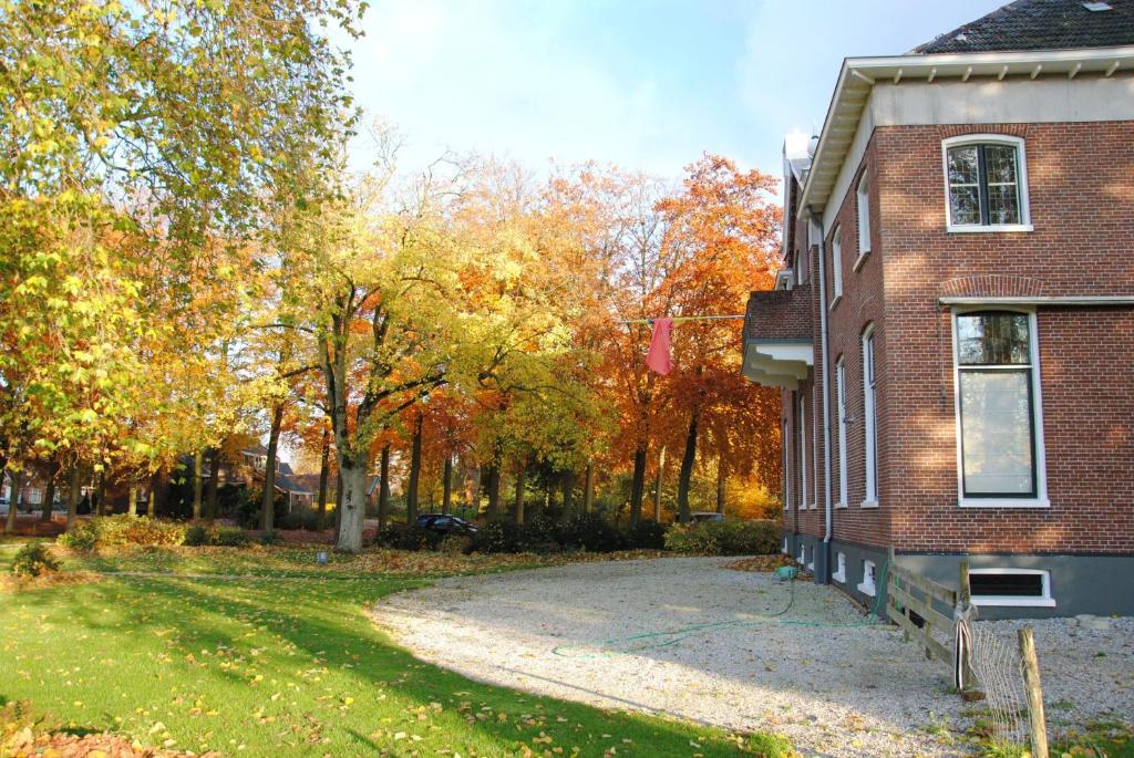 a driveway next to a brick house with trees at B&B Blauwestadhoeve in Midwolda