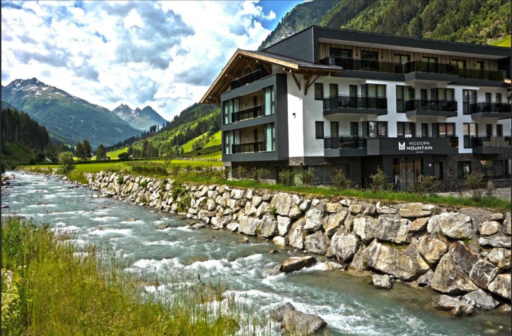a river with a stone wall next to it at Hotel Modern Mountain in Ischgl