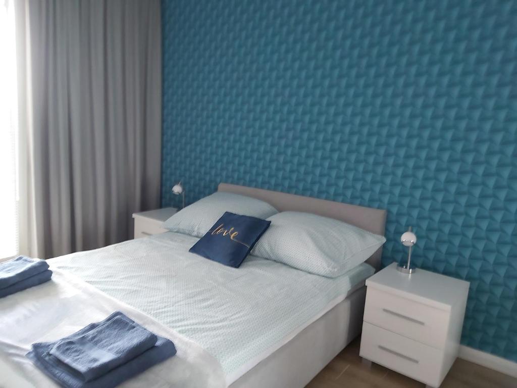 - une chambre dotée d'un lit avec un mur bleu dans l'établissement Przymorze Spectrum Apartment for you z halą garażową, à Gdańsk