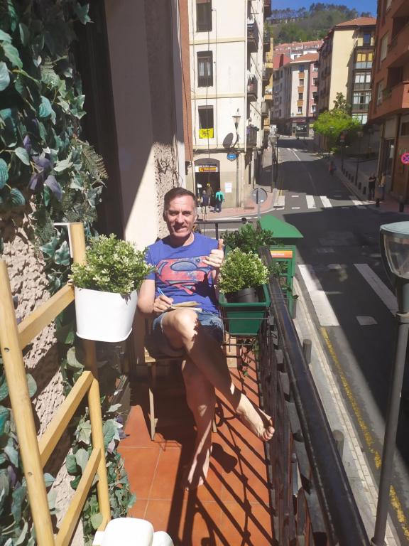 un hombre sentado en un balcón con plantas en Bilbao Center Apt PARKING, en Bilbao