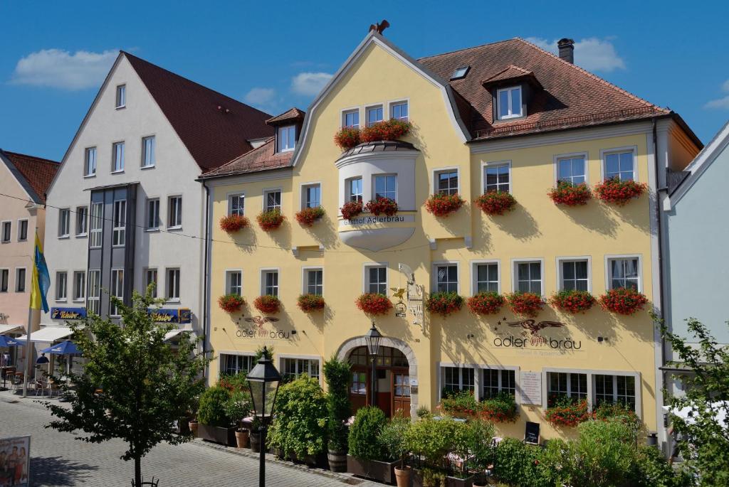 un edificio amarillo con flores en las ventanas en Land-gut-Hotel Hotel Adlerbräu, en Gunzenhausen