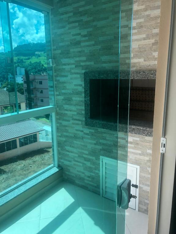 ducha con puerta de cristal y ventana en Apto Piratuba Termas, en Piratuba