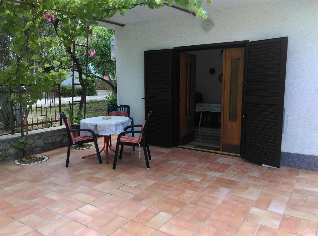un patio con mesa y sillas junto a una casa en Apartmani Vrzić, en Baška