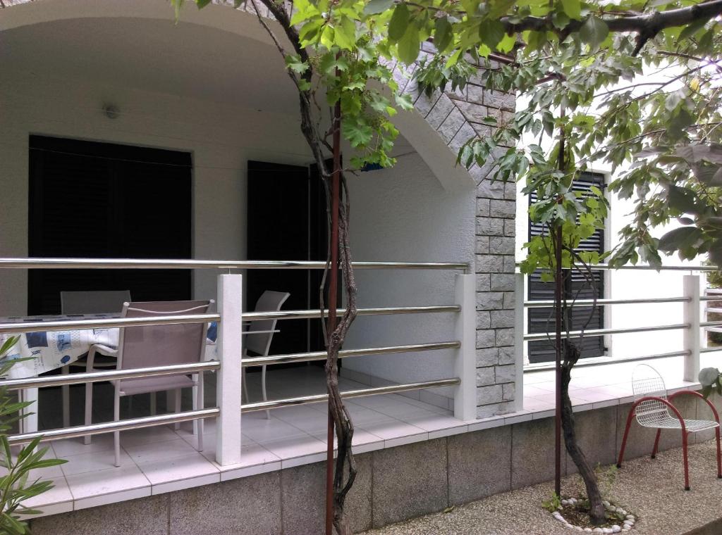 a porch with white railing and chairs and trees at Apartmani Vrzić in Baška