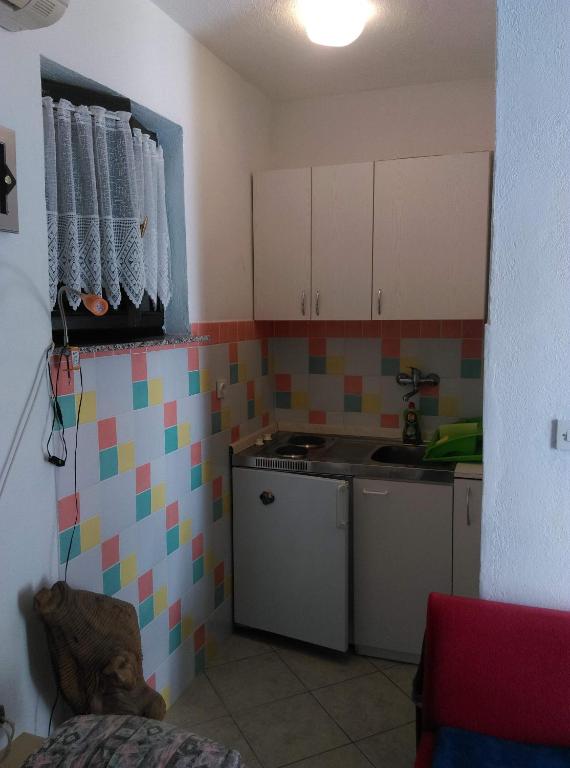 a kitchen with white cabinets and colorful tiles on the wall at Apartmani Vrzić in Baška
