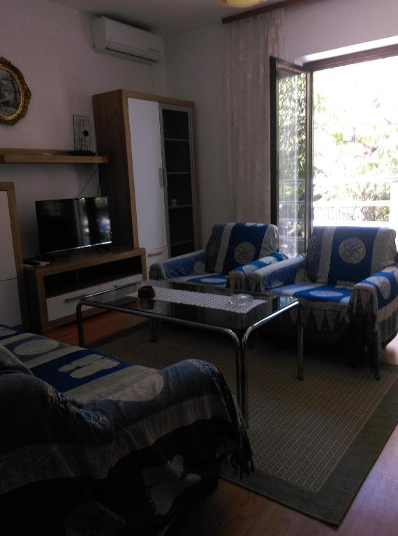 a living room with couches and a table and a window at Apartmani Vrzić in Baška