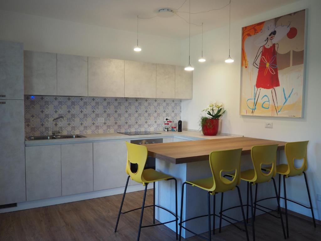 a kitchen with a wooden counter and yellow bar stools at Mami al Mare in Duino