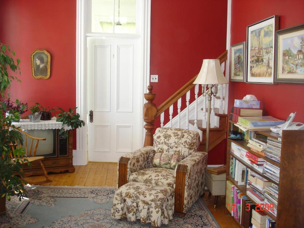 a living room with red walls and a chair at Le Gîte des Soeurs in Saint-Luc-de-Vincennes