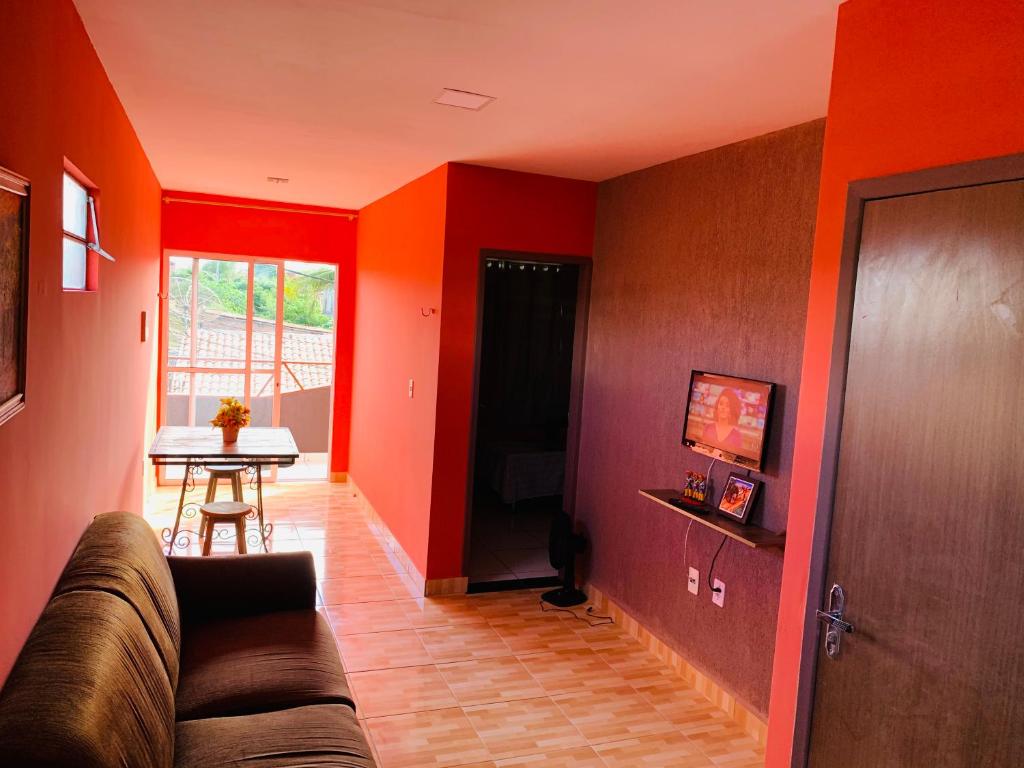 a living room with red walls and a couch and a table at Casa em Gravata mobiliada in Gravatá
