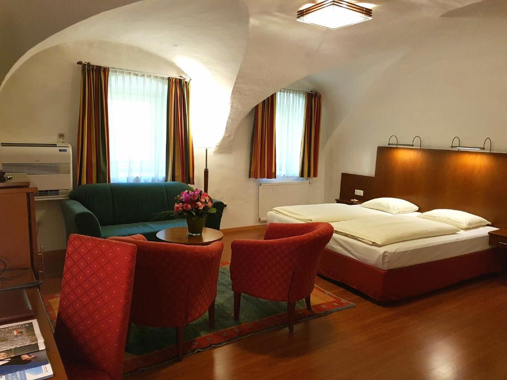 ein Schlafzimmer mit einem Bett und einem Tisch und Stühlen in der Unterkunft Hotel Via Roma in Salzburg