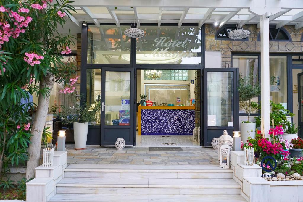 una tienda frente con la puerta abierta con flores rosas en Hotel Atlantis, en Nea Kalikratia