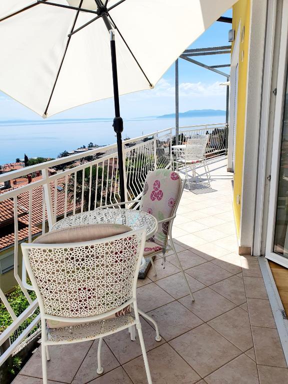 a patio with chairs and an umbrella on a balcony at Design Apartments Bonavista in Opatija
