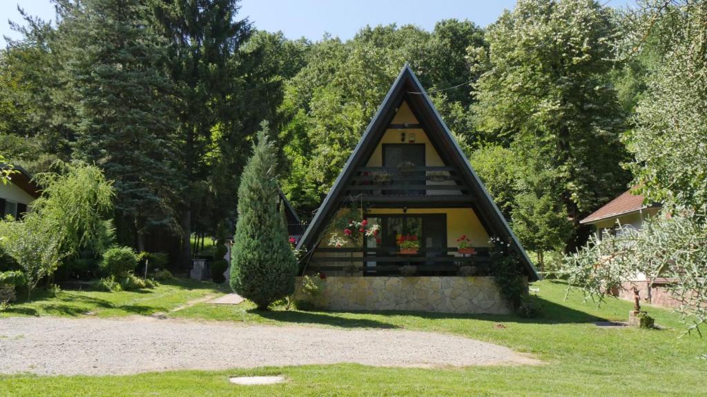 uma pequena casa com um telhado triangular num quintal em Planinska kuća "Zvuk Tišine" - Fruška gora em Beočin