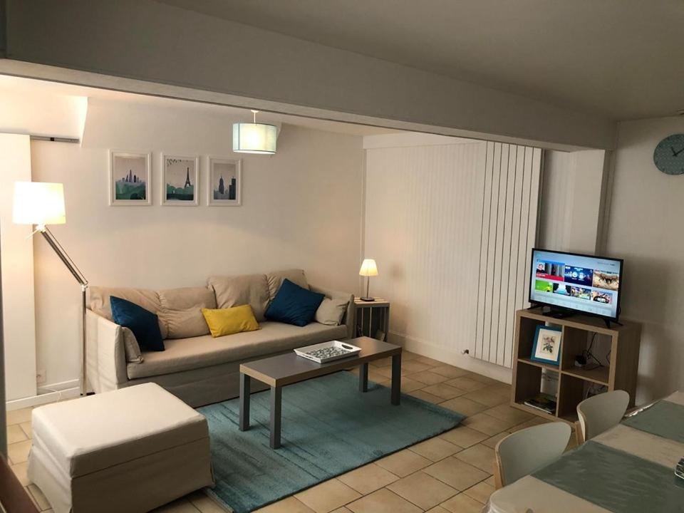 Una sala de estar con un sofá y un televisor. en L'HISTORIQUE - Maison rénovée dans le centre-ville de Bayeux, en Bayeux