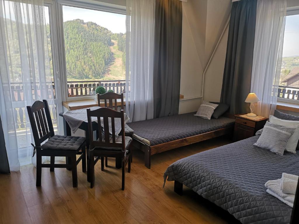 シュツァブニツァにあるWilla Tiramisuのベッド2台、テーブルと椅子が備わるホテルルームです。