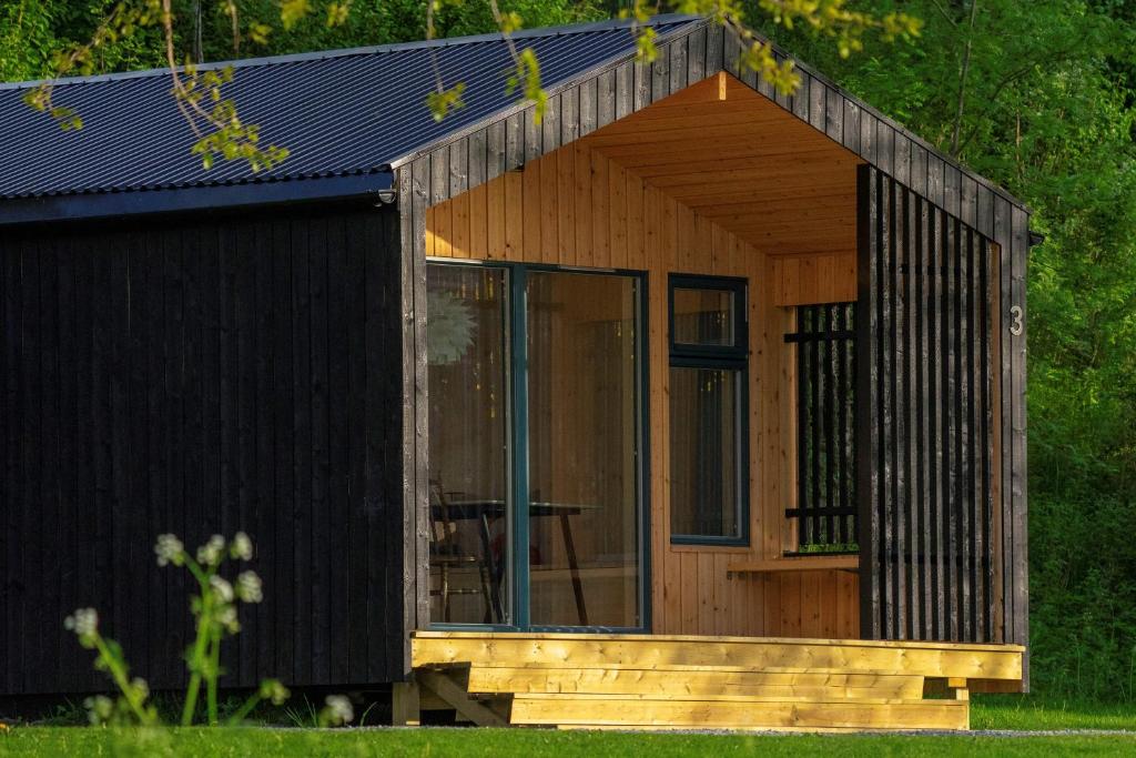 a wooden cabin with a porch and a glass door at FUGELVÅGEN, cabins and glamping 