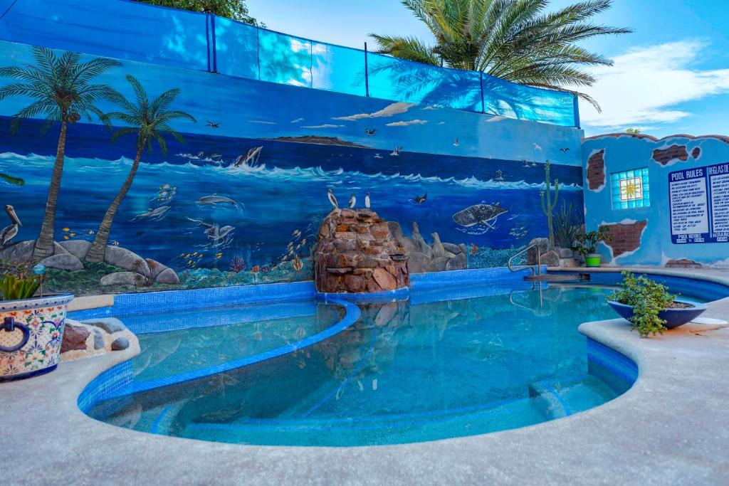 a pool in front of a blue wall with an aquarium at Hotel Posada Luna Sol in La Paz