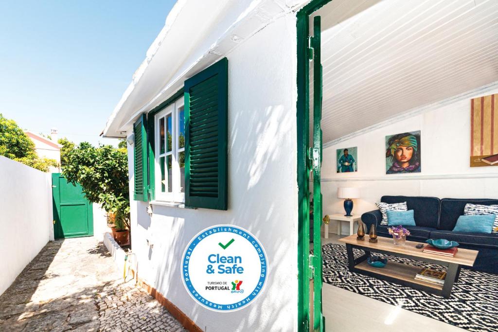 a white house with a green door and a living room at Casa Buganvília in Cascais