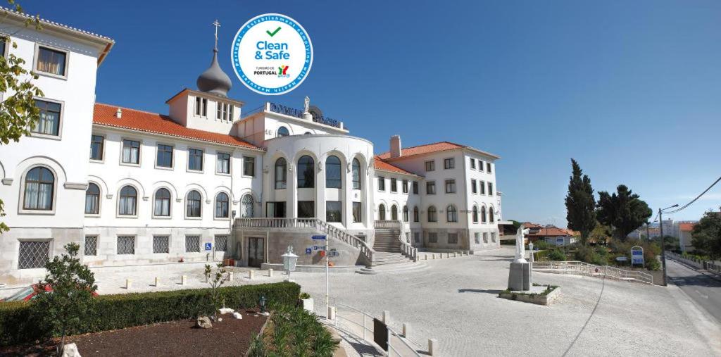 Un grand bâtiment blanc avec un panneau en haut dans l'établissement Domus Pacis Fatima Hotel, à Fátima