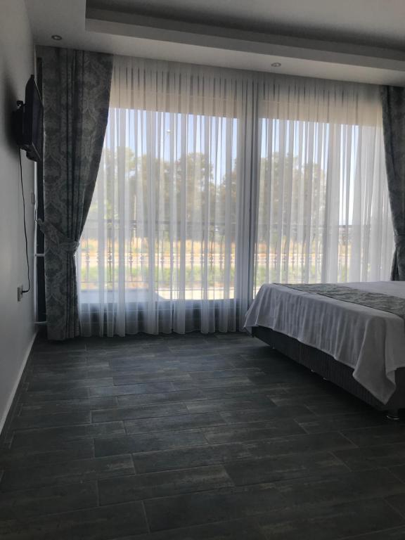 1 dormitorio con cama y ventana grande en Özbek Apart, en Ürkmez