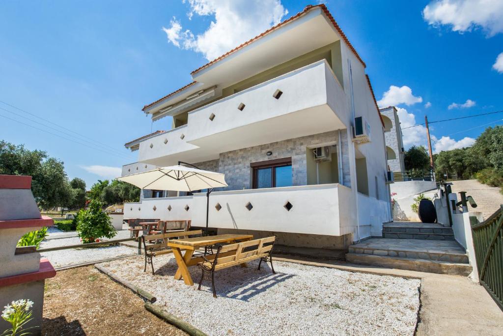 una casa con una mesa y bancos frente a ella en Olive Maison, en Astris