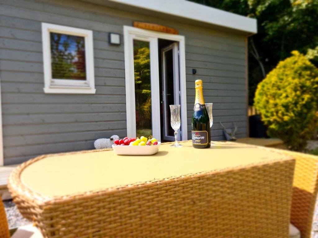 a bottle of champagne and a bowl of fruit on a table at Highland HotTub Retreat, on NC500 in Inverness