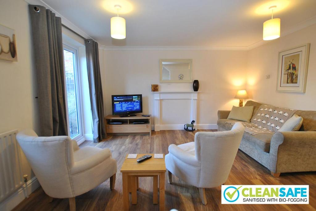 Cosy 2-Bedroom Cottages in Central Windsor في ويندسور: غرفة معيشة مع أريكة وكراسي وتلفزيون