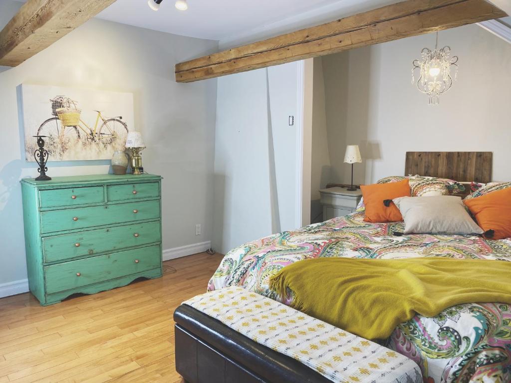 a bedroom with a green dresser and a bed at Domaine Steinbach Cidrerie B&B Distillerie in St-Pierre-de-l'Île-d'Orléans
