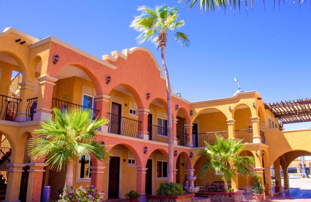 a building with palm trees in front of it at Hotel Angra in Loreto