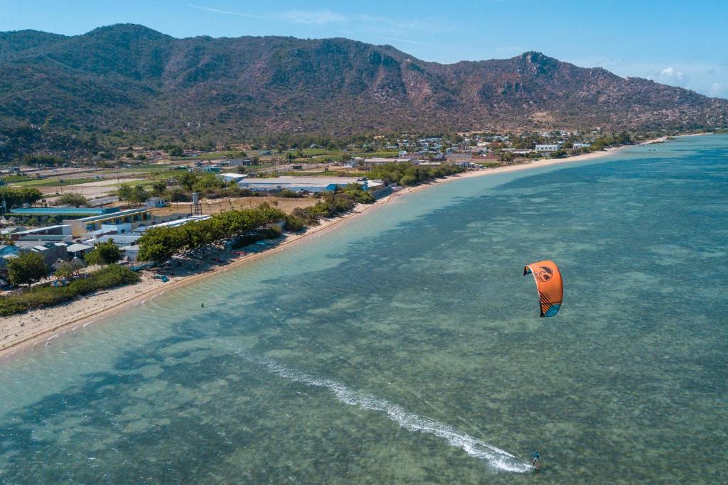 Phi Kite School في فان رانغ: طائرة ورقية برتقالية تطير فوق الشاطئ