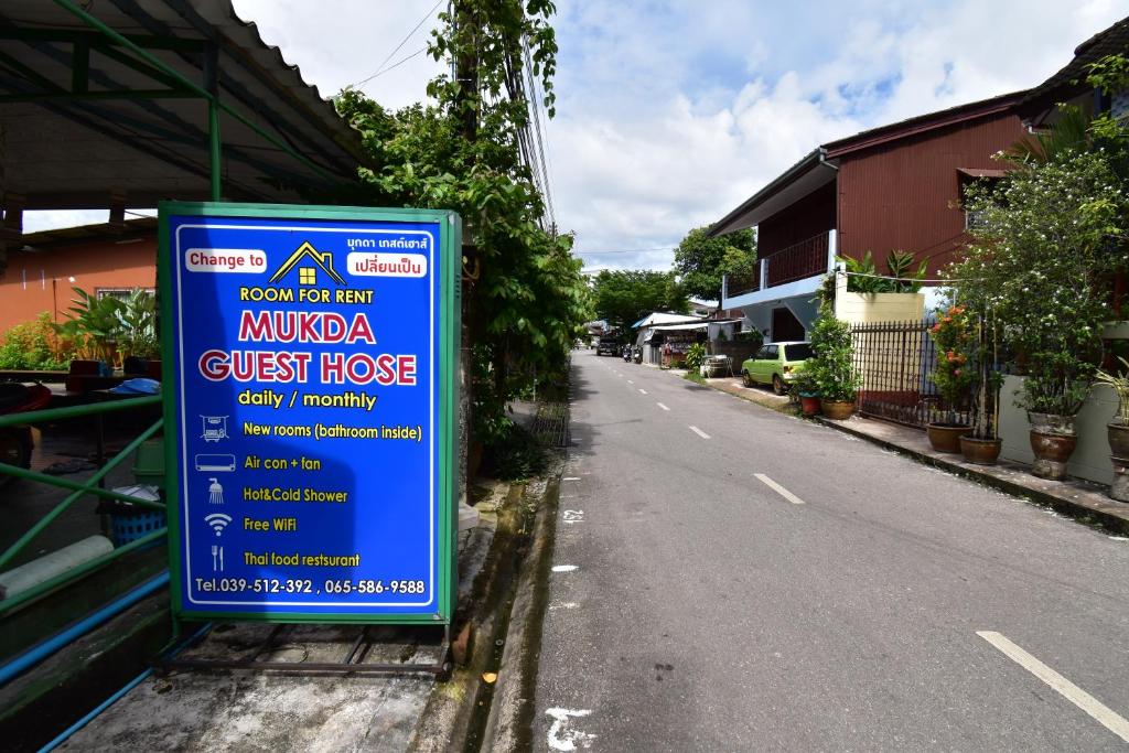 um sinal que está do lado de uma rua em Mukda Guesthouse em Trat