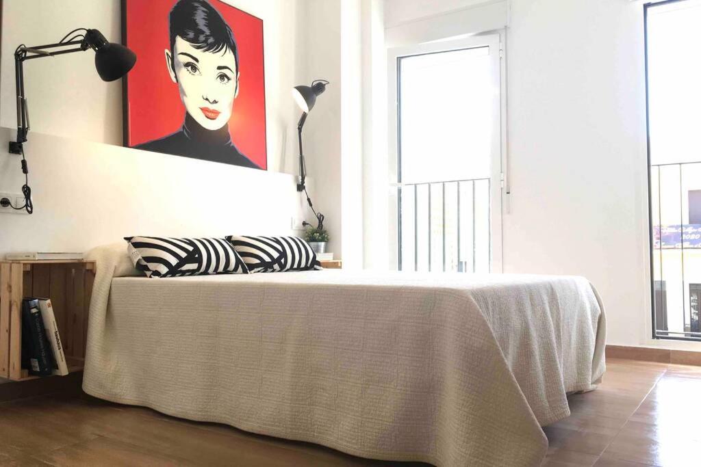 1 dormitorio con 1 cama con una pintura en la pared en Casa La Placeta, en Fortaleny