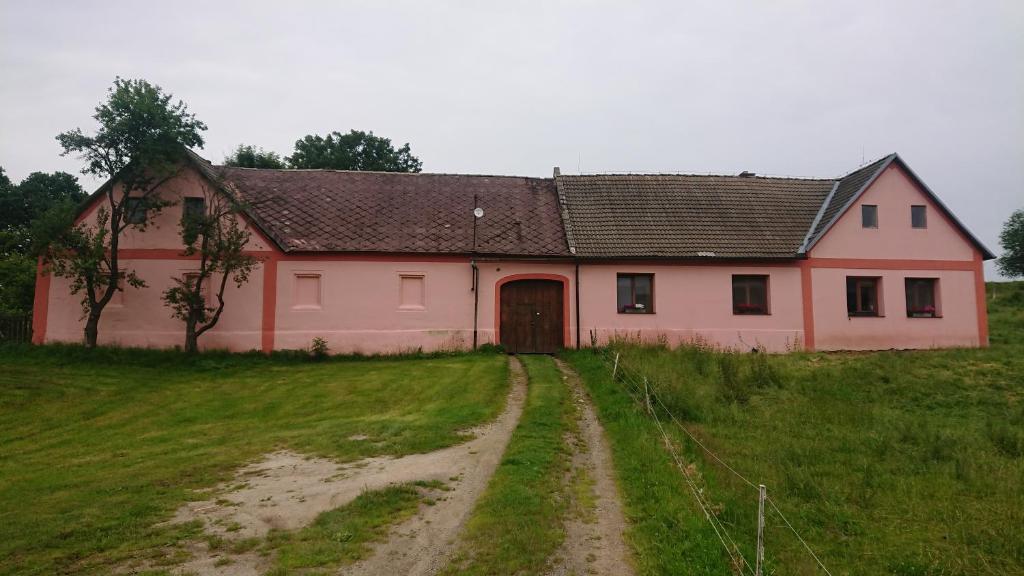 a pink house on a field with a dirt road at Ubytování na farmě v Novohradských horách in Horní Stropnice