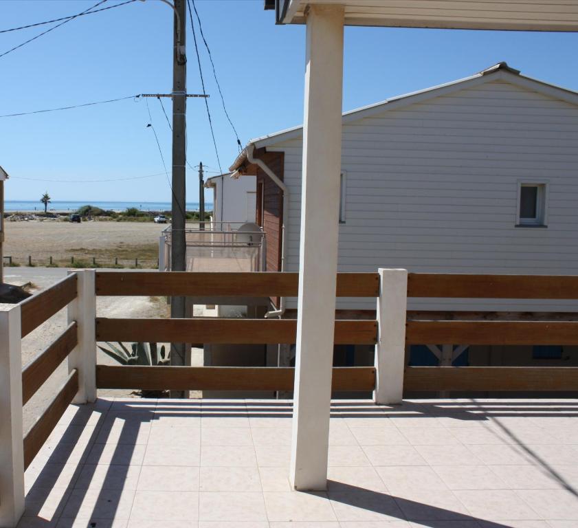 a wooden fence next to a building and a beach at Au Macareux in Gruissan