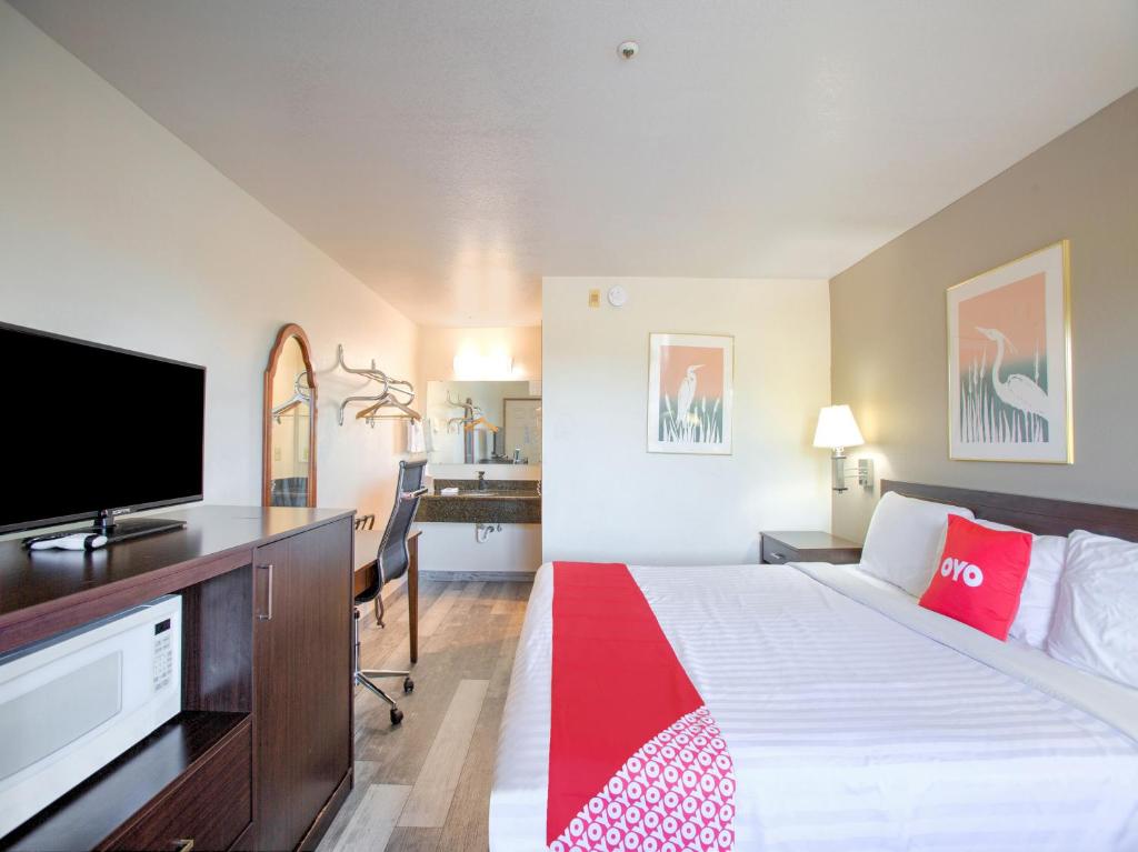 a hotel room with a bed and a flat screen tv at OYO Woodland Hotel and Suites in Woodland