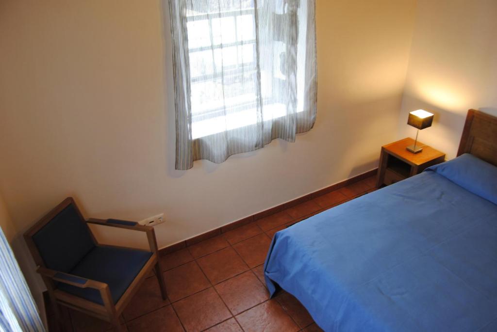 a bedroom with a bed and a chair and a window at Casas Da Faja in Praia do Norte
