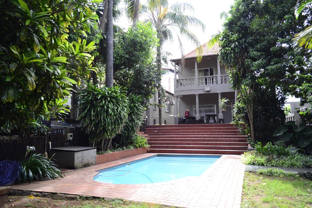 a swimming pool in front of a house at Laletsa Lodge in Durban