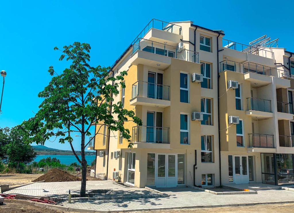 a yellow building with a tree in front of it at Семеен хотел Сирена in Ahtopol