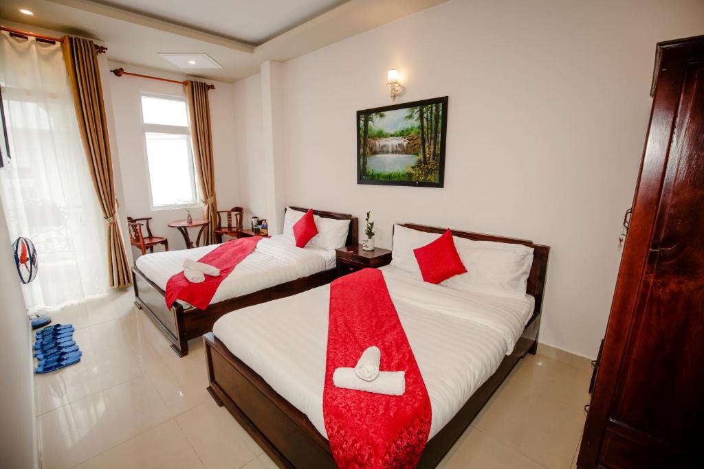 due letti in una stanza con cuscini rossi sopra di Conico Đà Lạt Hotel a Da Lat