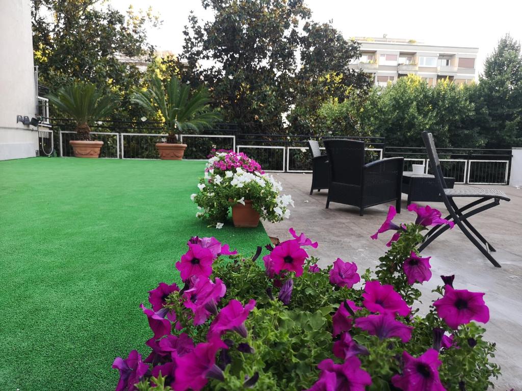 eine Terrasse mit Blumen und Stühlen auf einem Rasen in der Unterkunft Guest House Arte in Rom