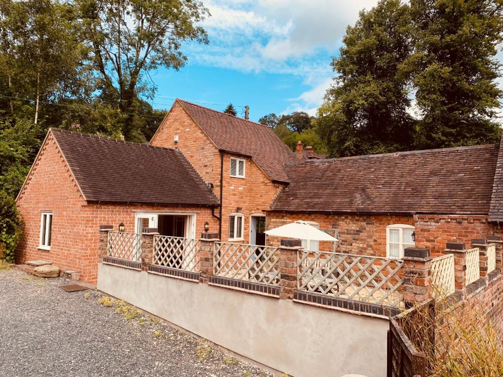 a brick house with a balcony with an umbrella at Dale Cottage in Ironbridge