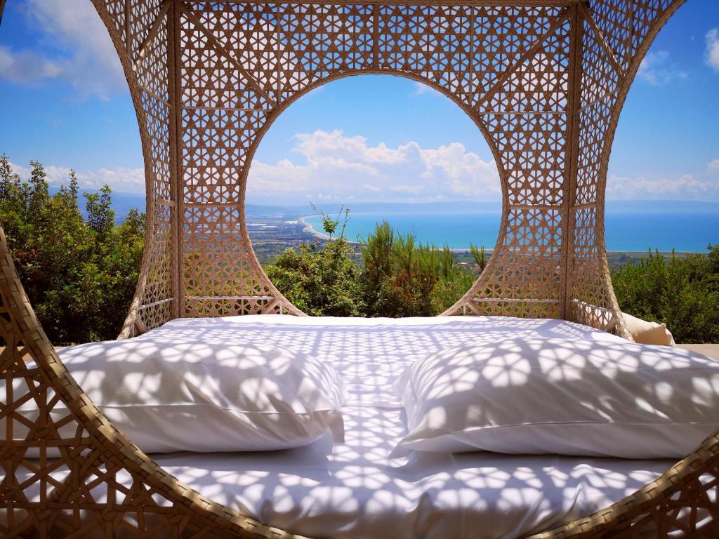 - un lit dans une chaise en osier avec vue sur l'océan dans l'établissement Due Esperienza Panoramica, à Lamezia Terme