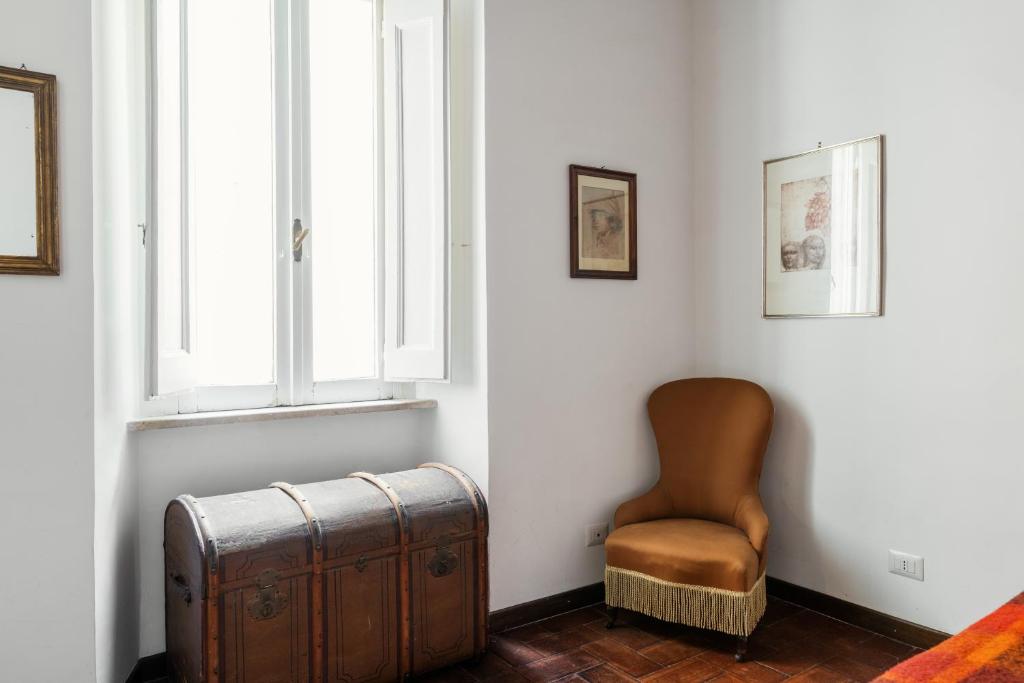 a room with a chair and a trunk and a window at Domus Quiritum Charming, Appartamento d'Epoca a Campo de' Fiori in Rome