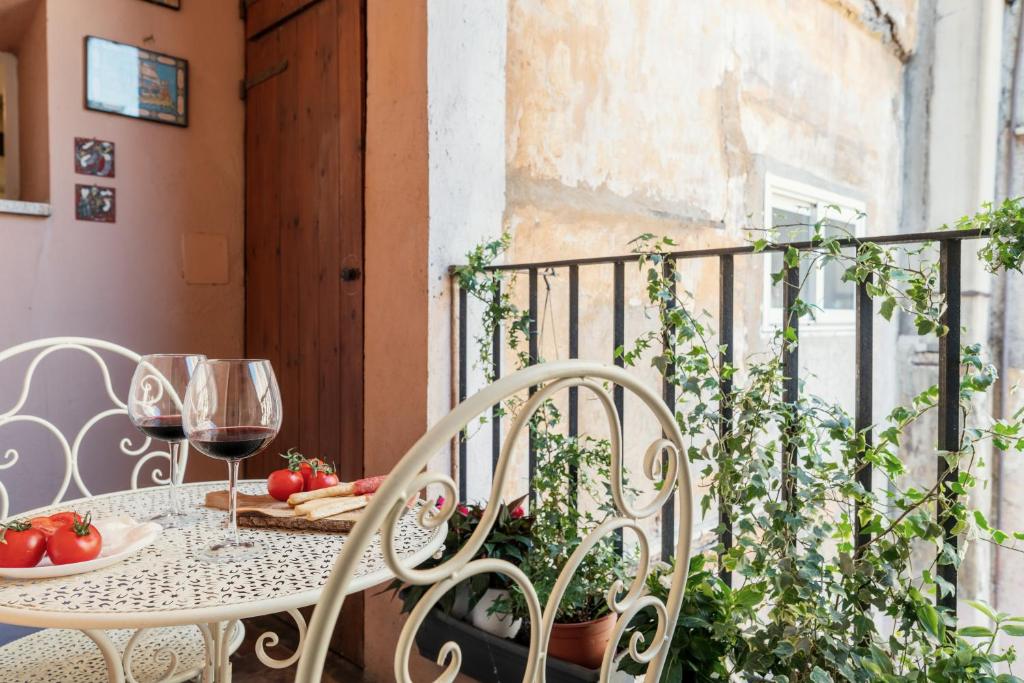 a table and chairs on a balcony with wine glasses at Domus Quiritum Charming, Appartamento d'Epoca a Campo de' Fiori in Rome