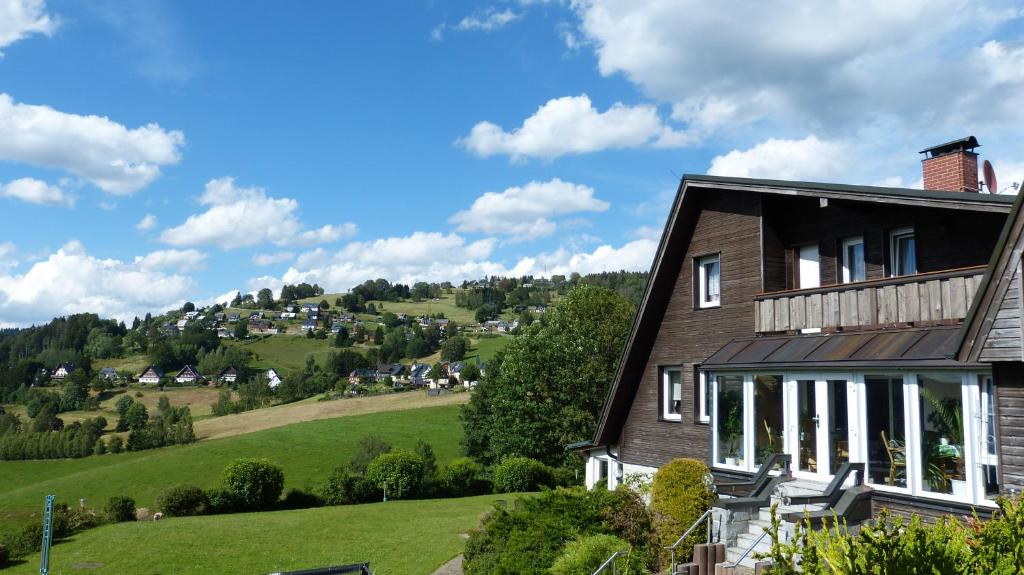 ein Haus auf einem Hügel mit einem grünen Feld in der Unterkunft Domizil Aschbergblick in Klingenthal